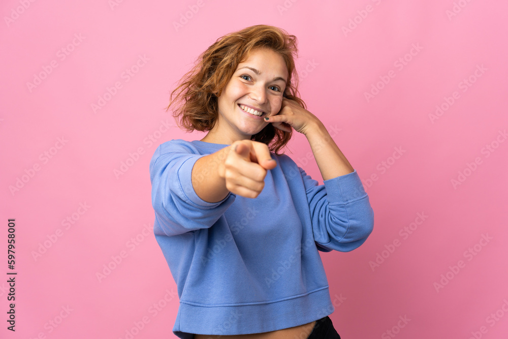 Young Georgian woman isolated on pink background making phone gesture and pointing front Young Georgian woman isolated on pink background making phone gesture and pointing front