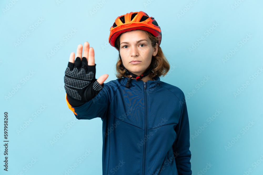 Young cyclist woman isolated on blue background making stop gesture Young cyclist woman isolated on blue background making stop gesture