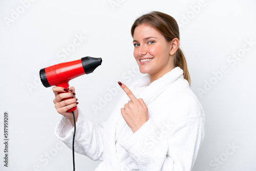 Young caucasian woman holding hairdryer isolated on white background and pointing it