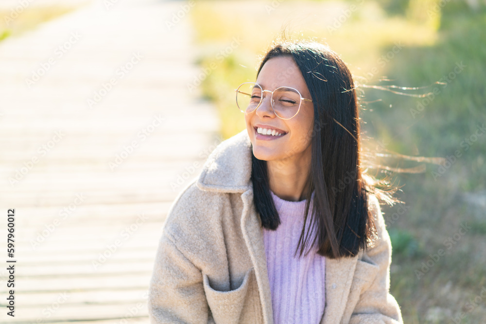Young woman at outdoors With glasses with happy expression