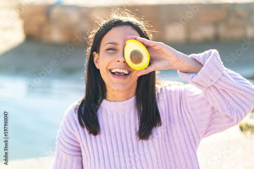 Young woman at outdoors holding an avocado at outdoors