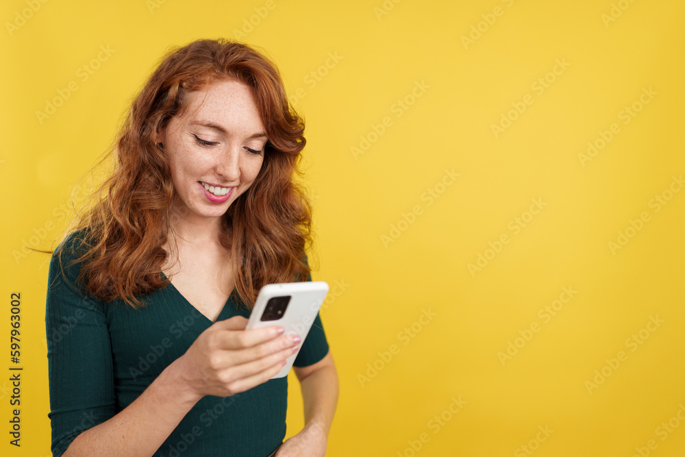 Happy redheaded woman smiling while using the mobile Happy redheaded woman smiling while using the mobile