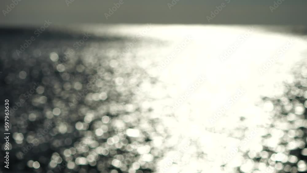 Abstract shining sun reflections on blue surface of sea waves. Bokeh sun glare reflected in water surface. The shimmering small sea waves in sun. Sea on sunny day. Natural bokeh texture. Slow motion Abstract shining sun reflections on blue surface of sea waves. Bokeh sun glare reflected in water surface. The shimmering small sea waves in sun. Sea on sunny day. Natural bokeh texture. Slow motion
