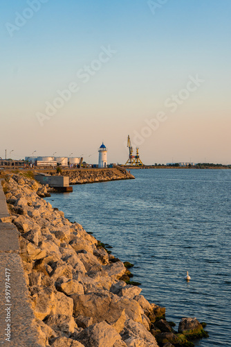 The rocky pontoon, at the end of which there is a round tower with a blue roof, which is the lighthouse in the port