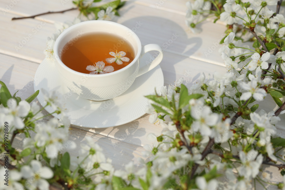 cup of tea with cherry blossom decoration on white wooden background. cup of tea with cherry blossom decoration on white wooden background.