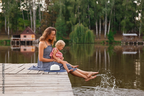 mother and daughter walk on the bridge by the water, girl in a hat on a wooden bridge, walk by the pond, pond, family near the lake

