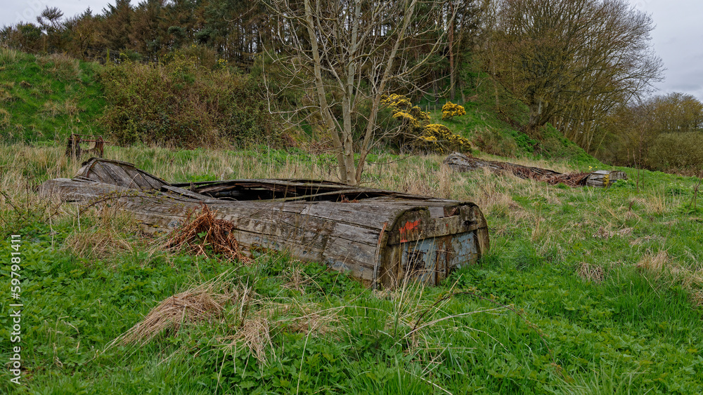 Two wooden Old and abandoned Fishing Boats or Skiffs lying upturned on the Banks of the River North Esk at Kinnaber Links near to Montrose.