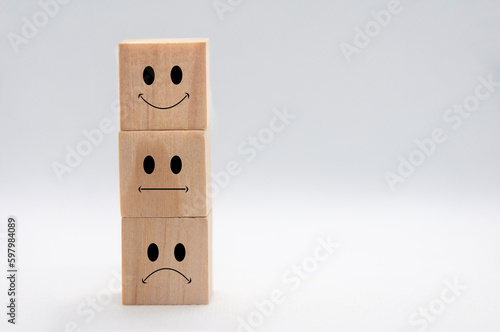 Happy, sad and neutral emotion faces on stacking wooden cubes with white background cover. Customer satisfaction and evaluation concept.