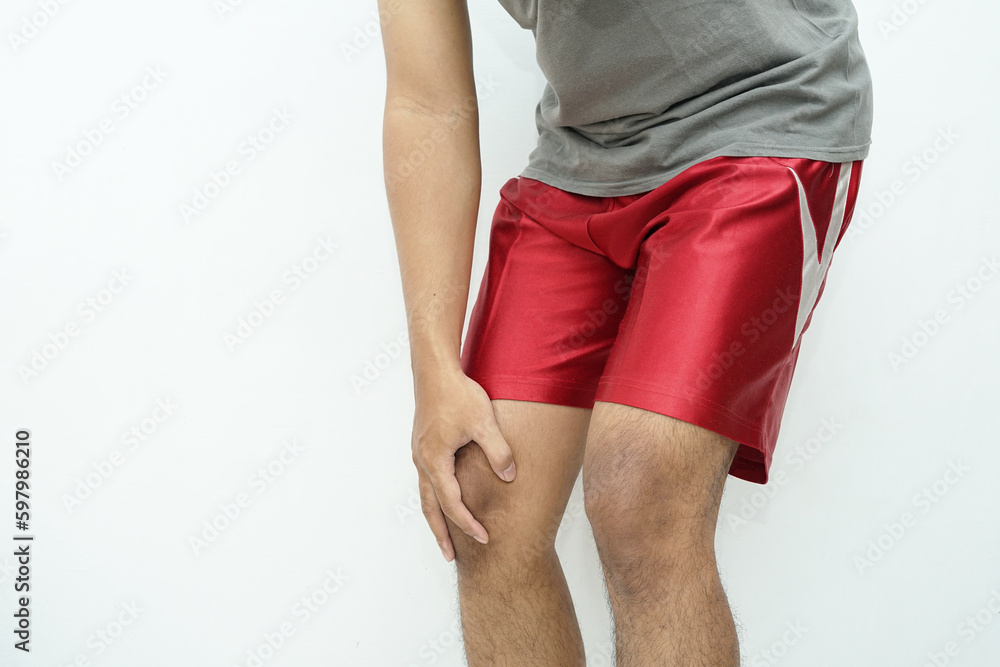 An Asian man holds his knee due to pain, injury or fatigue