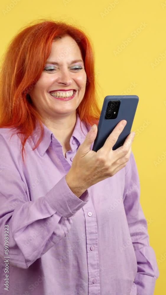 Happy mature redheaded woman smiling while using the mobile Happy mature redheaded woman smiling while using the mobile