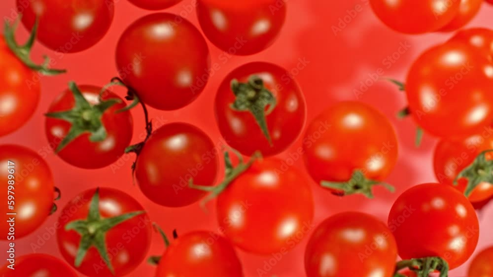 Super slow motion of cherry tomatoes flying on red background. Filmed on high speed cinema camera, 1000 fps. Camera placed on high speed cine bot, tracking the target. Super slow motion of cherry tomatoes flying on red background. Filmed on high speed cinema camera, 1000 fps. Camera placed on high speed cine bot, tracking the target.