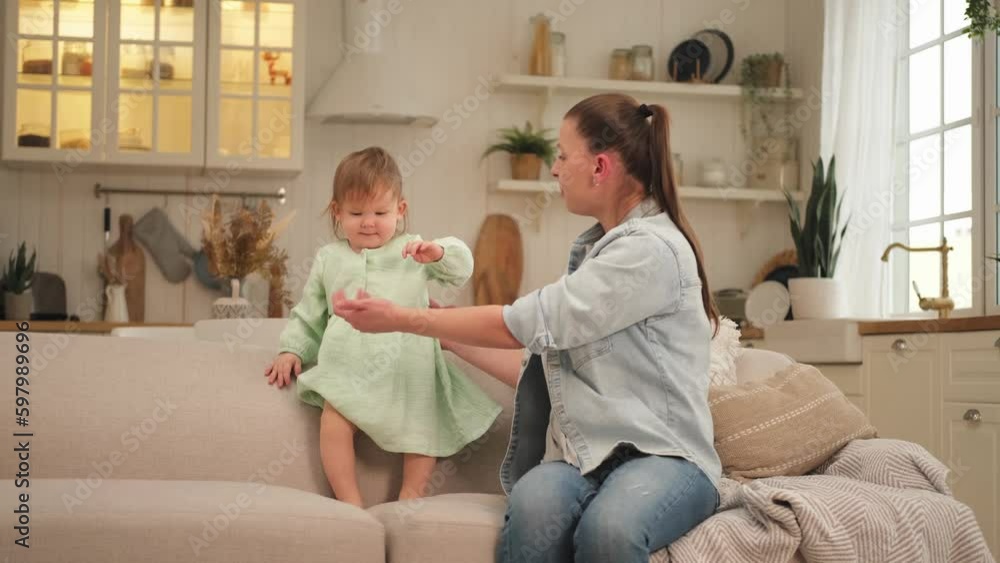 Happy family at home. Mother and baby girl playing in couch at home indoors. Little toddler child and babysitter nanny having fun together. Young woman mom kid daughter rest in living room Happy family at home. Mother and baby girl playing in couch at home indoors. Little toddler child and babysitter nanny having fun together. Young woman mom kid daughter rest in living room