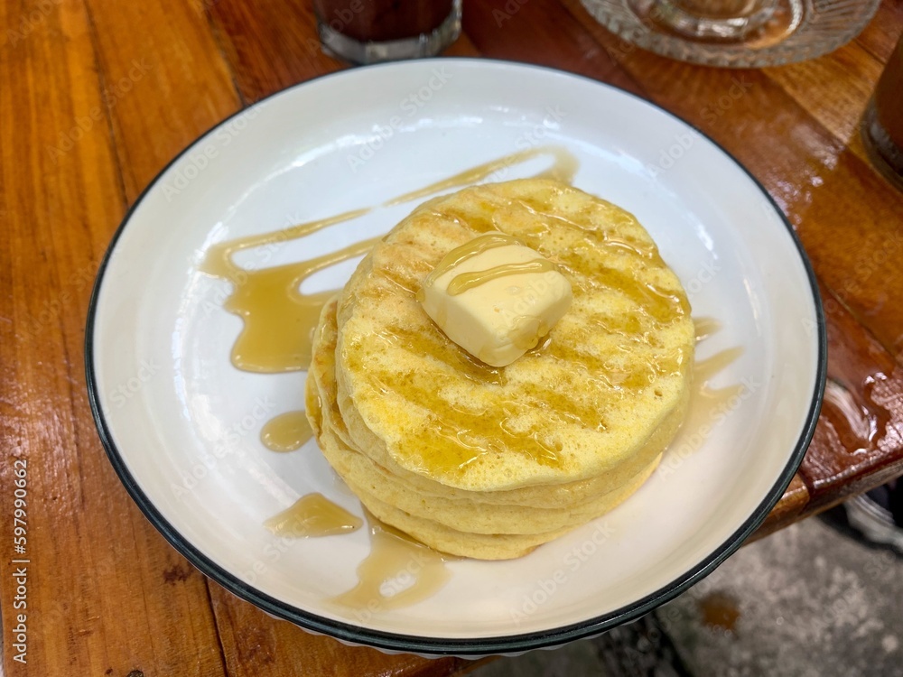 Stack of plain pancakes with butter and honey on a white plate Stack of plain pancakes with butter and honey on a white plate
