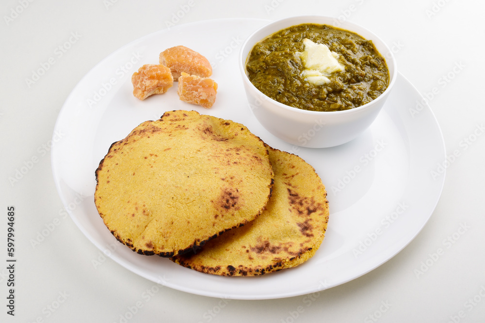 Sarso saag with makki roti served with jaggery in white plate isolated on white background, punjabi food Sarso saag with makki roti served with jaggery in white plate isolated on white background, punjabi food