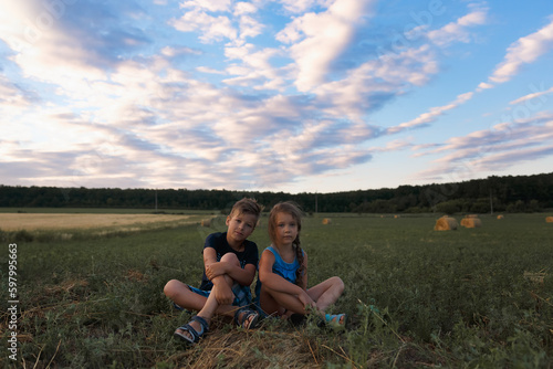 Children on round bales, mowed wheat, bales of wheat, children in Ukraine, wheat field, children in a wheat field with a beautiful sky, bales