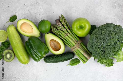 Healthy vegetarian food: green vegetables and herbs on a gray background. Top view. Assorted green vegetables: broccoli, beans, avocado, zucchini, kiwi, asparagus. Alkaline diet. Banner. 