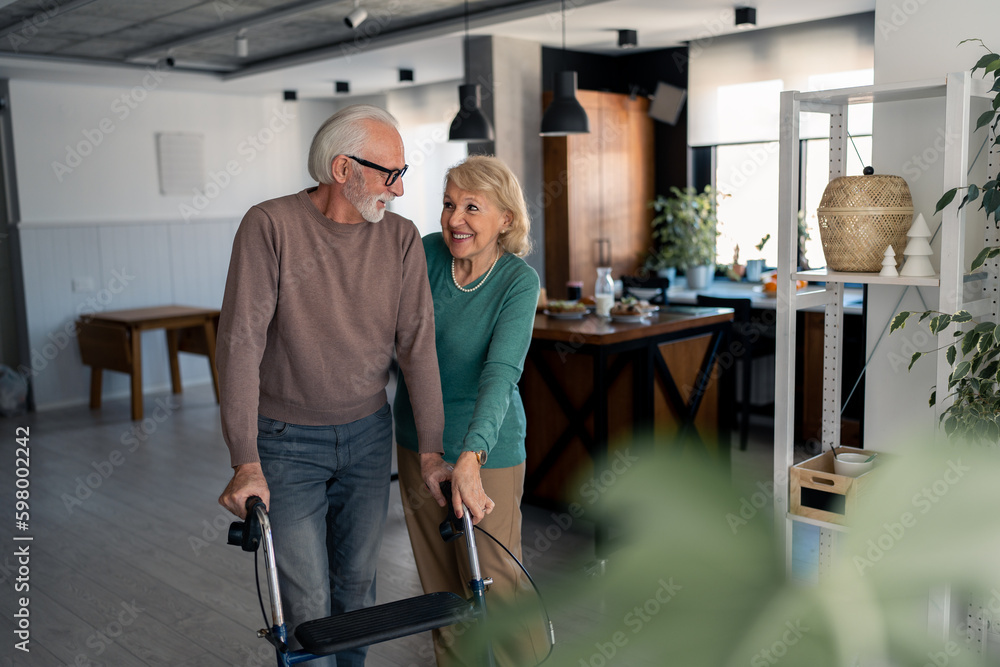 Caring wife assisting her husband to walk step by step with mobility