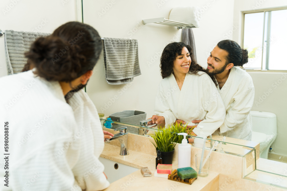 Loving couple hugging while using beauty products in the bathroom Loving couple hugging while using beauty products in the bathroom
