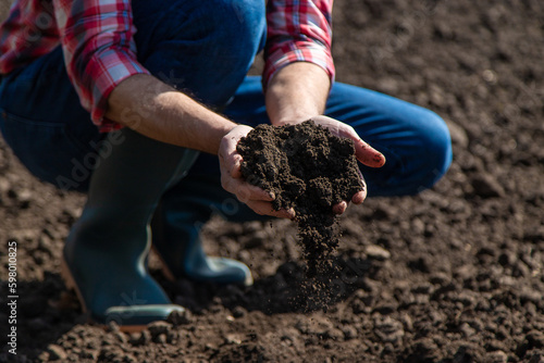 Male farmer in the field checks the soil. Selective focus.