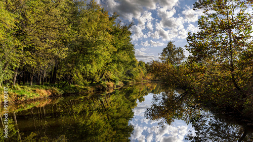 .Landscape with a canal reflecting trees and a cloudy sky at Creve Coeur park near St. Louis, Missouri