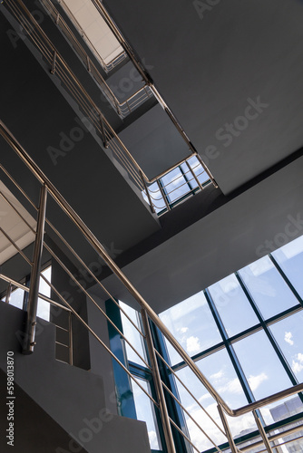 Stairs in a concrete office building in neutral tones, covered with ceramic tiles, with shiny metal railings