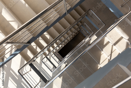 Stairs in a concrete office building in neutral tones  covered with ceramic tiles  with shiny metal railings