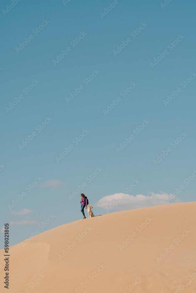 Woman with a dog on Patara Beach Turkey, clouds above.