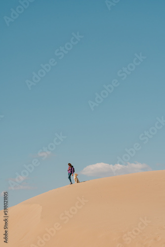 Woman with a dog on Patara Beach Turkey  clouds above.