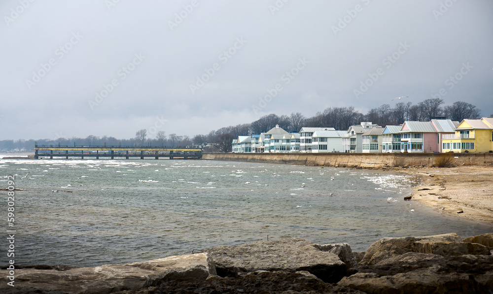 View of Lake Erie in spring. Ice floes on the lake. Pier and houses by the lake. Crystal Beach Waterfront, Ontario, Canada