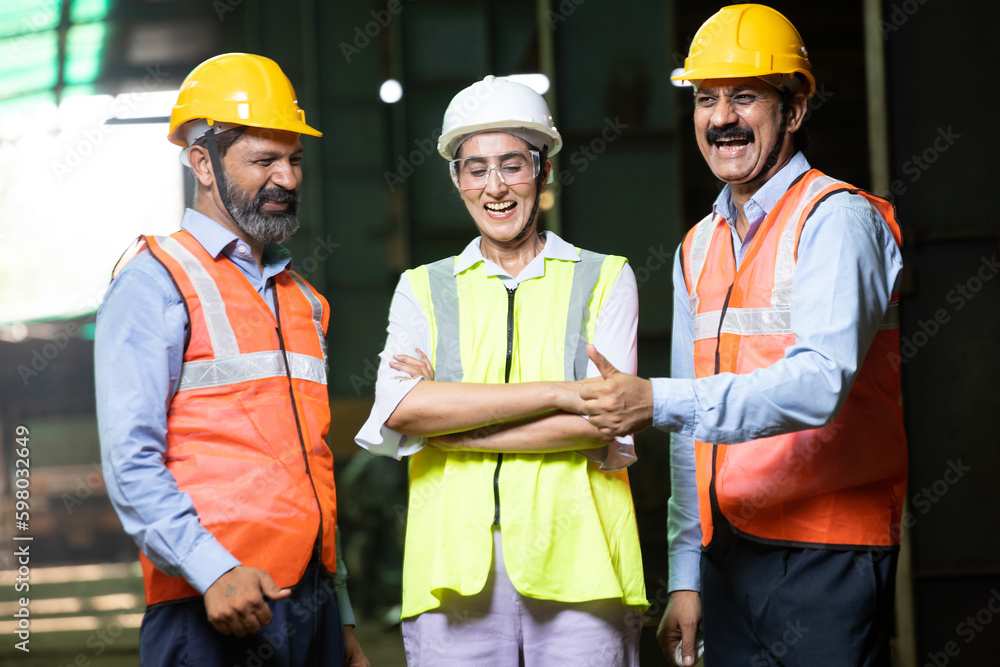 Team of happy confident indian engineers wearing safety hard hat and vest standing at industrial factory, male and female professional workers looking at camera, skill india. Team of happy confident indian engineers wearing safety hard hat and vest standing at industrial factory, male and female professional workers looking at camera, skill india.