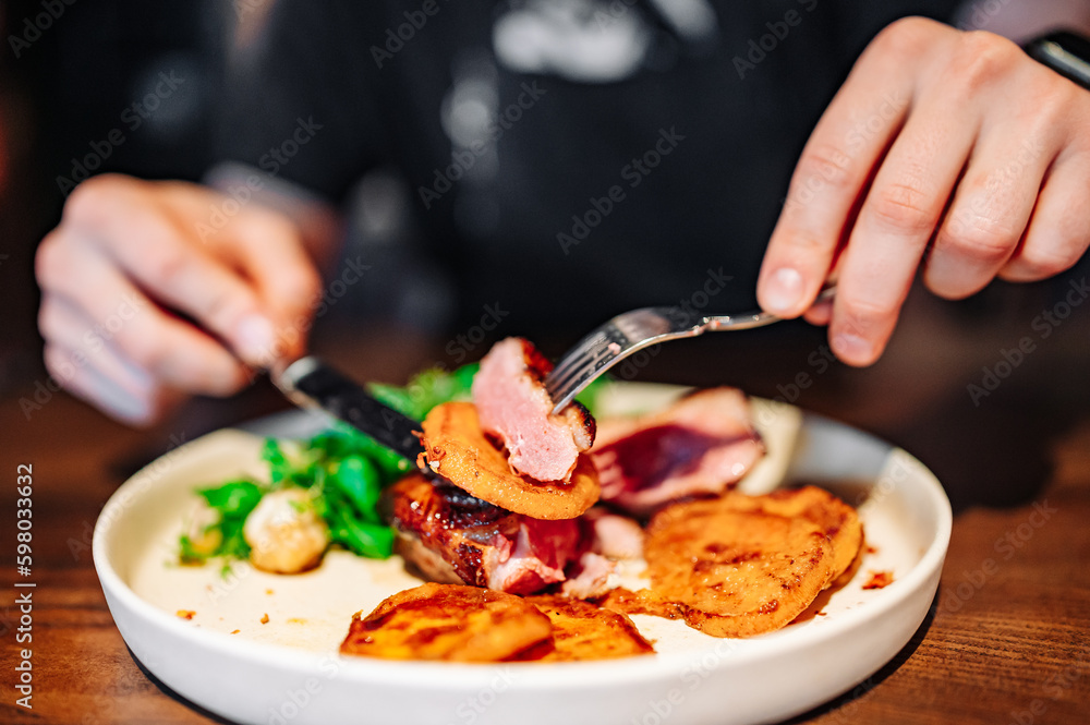 man with a knife and fork cuts grilled duck meat man with a knife and fork cuts grilled duck meat