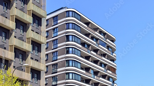 Modern apartment buildings on a sunny day with a blue sky. Facade of a modern apartment building. Contemporary residential building exterior in the daylight.  © Grand Warszawski