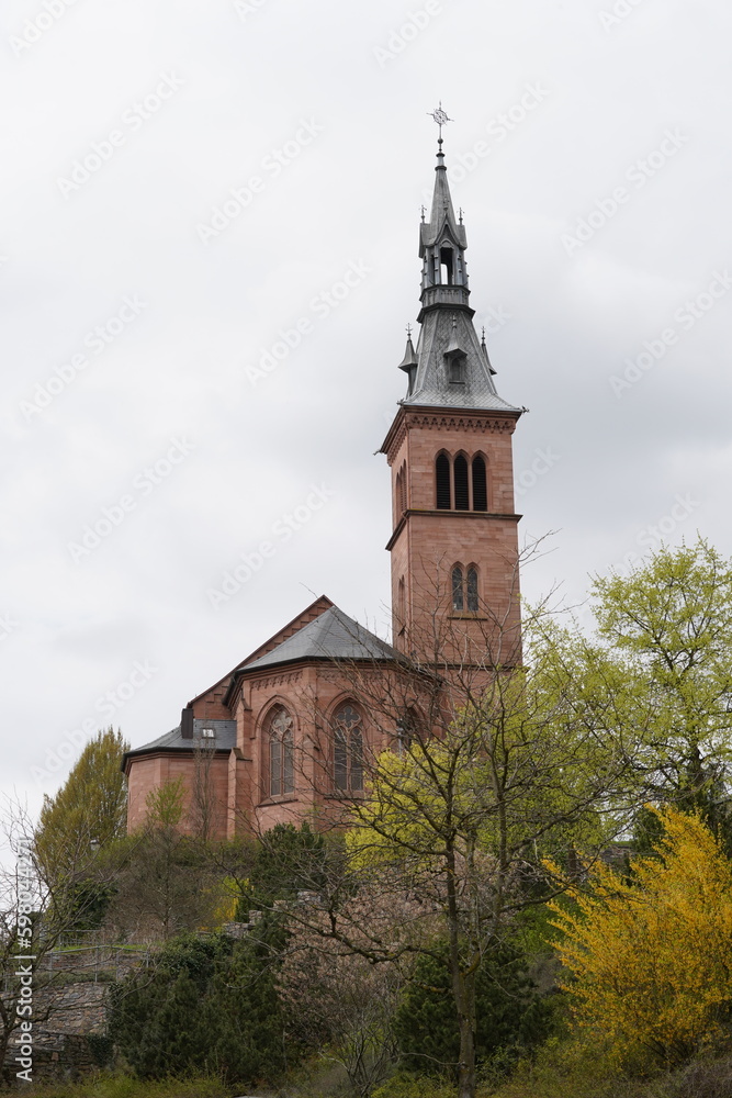 Catholic Church of Holy Spirit in low angle view. On background is blue sky slightly overcast with white clouds and trees with fresh green leaves at springtime.