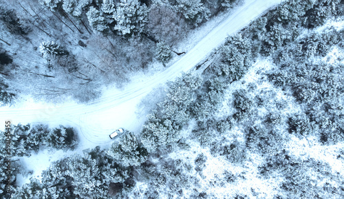 white car is moving at high speed on a snowy forest road. Drone photo. © MARINA