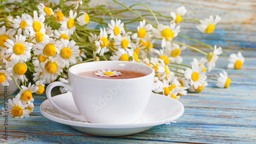 Fototapeta Naklejka Na Ścianę i Meble -  Daisy flowers in a white cup of tea, chamomile herbs on wooden background. Herbal medicine. Healthy lifestyle concept.