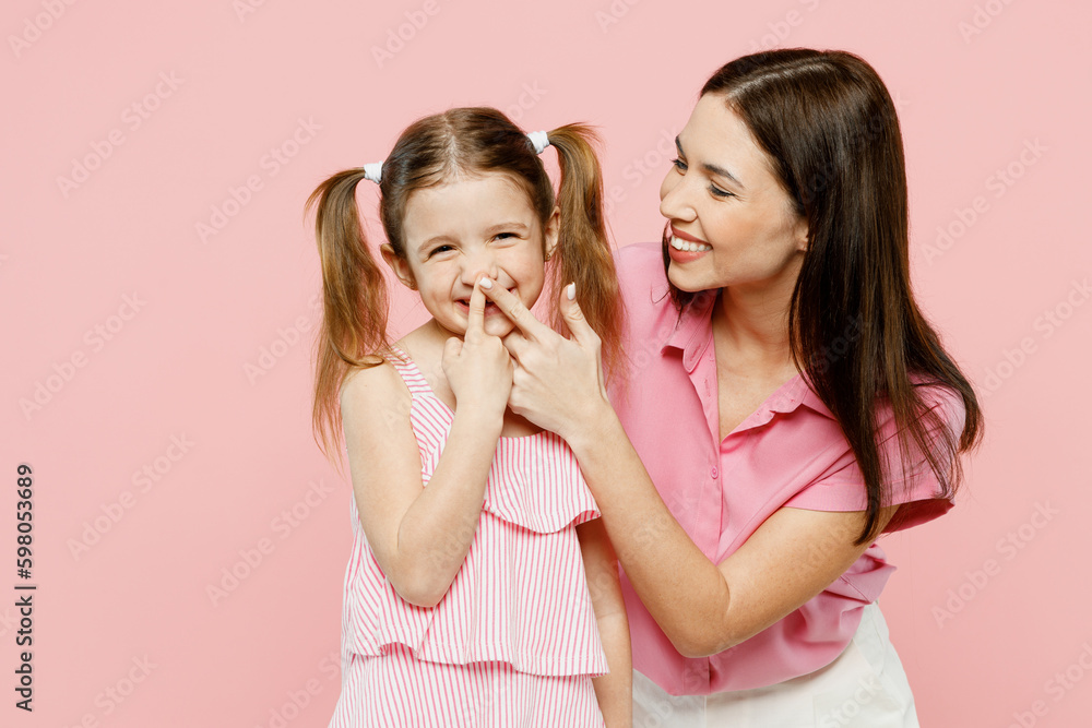 Happy cheerful smiling fun woman wear casual clothes with child kid girl 6-7 years old. Mother touch nose of daughter look camera isolated on plain pastel pink background. Family parent day concept. Happy cheerful smiling fun woman wear casual clothes with child kid girl 6-7 years old. Mother touch nose of daughter look camera isolated on plain pastel pink background. Family parent day concept.