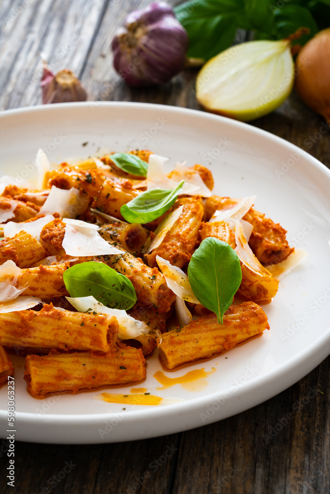 Noodles with pesto, parmesan cheese and basil leaves served on wooden table
