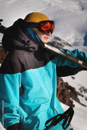 young male skier in ski goggles stands with skis on his shoulder ready for competition. sportsman portrait © yanik88