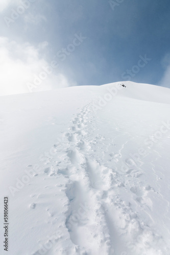Landscape of snowy mountains with footprint on the snow during daytime in cloudy weather