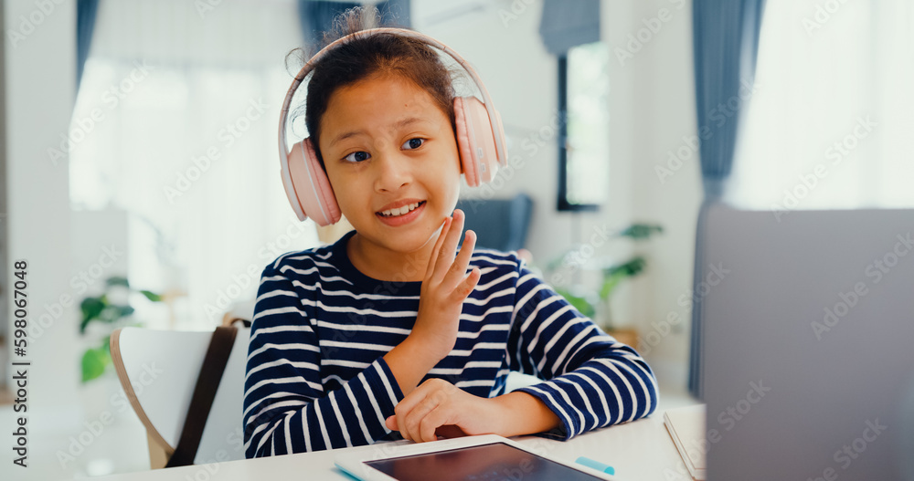 Asian toddler girl with sweater wear headphone sit front of desk with notepad use magic pen focus on writing do homework, finger counting number math online learning course from laptop at home. - obrazy, fototapety, plakaty 