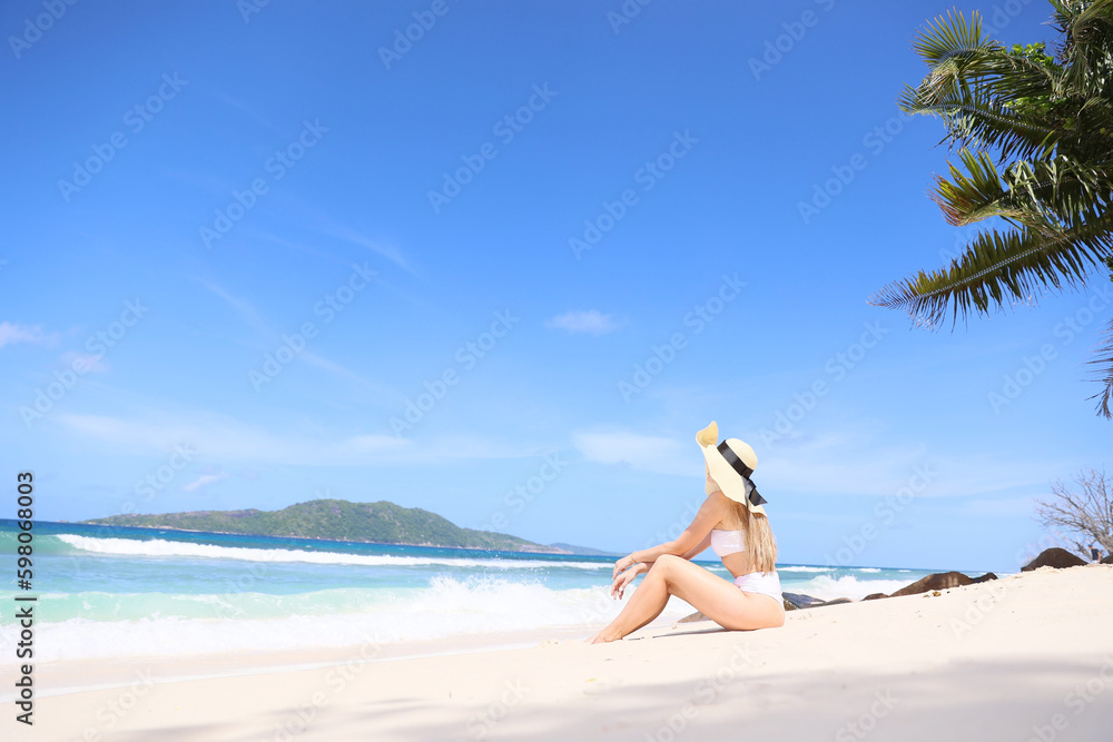 Summer vacation fashion concept - sunbathing woman in sun hat on the beach on white sand. Summer vacation fashion concept - sunbathing woman in sun hat on the beach on white sand.