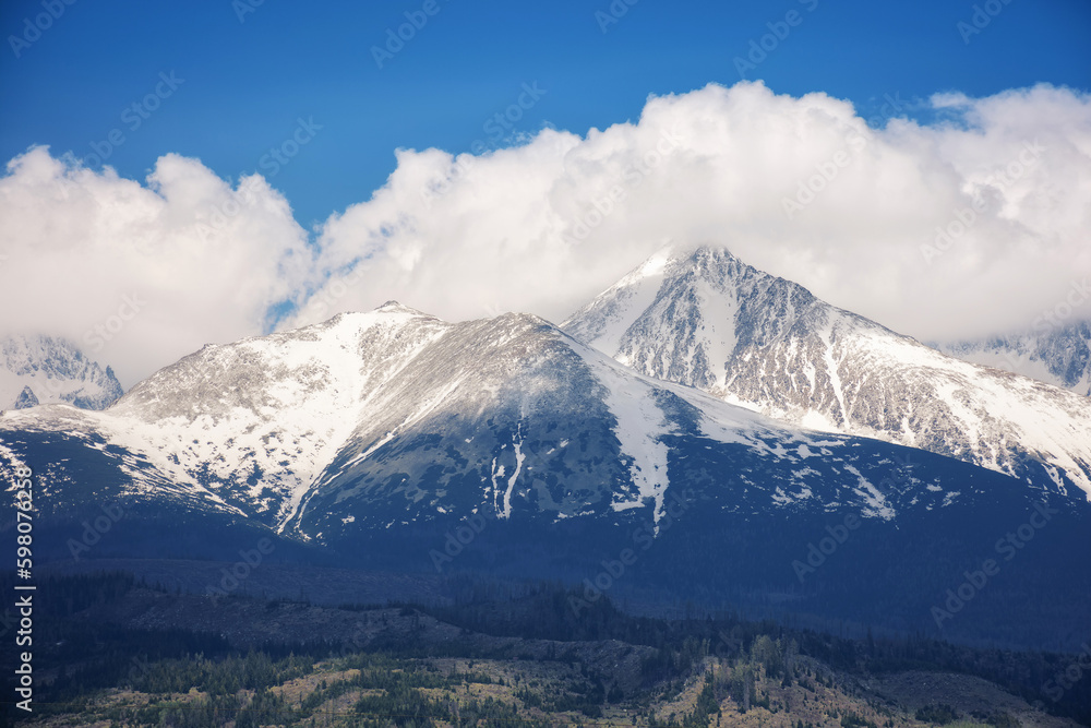 nature background of mighty high tatra ridge in spring at high noon. snowcapped rocky peaks beneath a cloudy sky