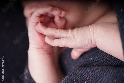 A tiny cute baby born one week old. Newborn peeling. Newborn Baby's hands and face skin with skin peels. close up of hands new baby born details.