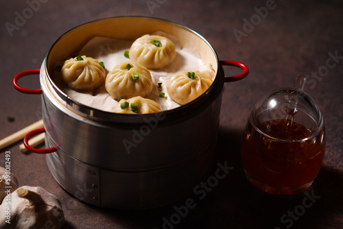 Traditional dumplings in bamboo steamer with sauces and chopsticks on dark  wooden surface with copy space  food background  dumpling steamer basket  gyoza  dimsum   menu  oriental  fine dining