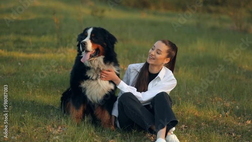 Bernese Mountain Dog (Bernese Mountain Dog)
Long-haired teenage girl hugs and kisses her beautiful big dog while enjoying playing on the lawn. Children and pets concept.