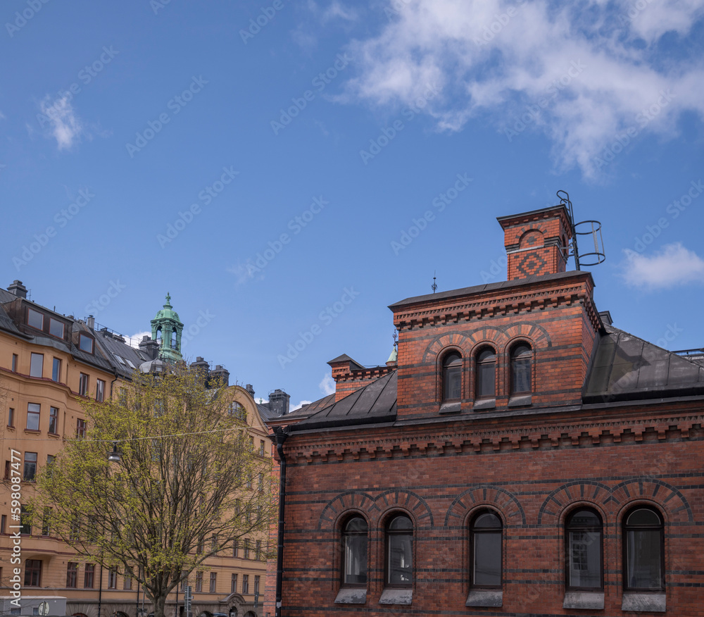 Roof, dorms and chimney on the old royal stable brick houses in the district Östermalm, a sunny spring day in Stockholm