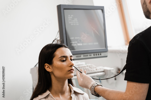 ENT doctor using fibrolaryngoscope to examine and treat nose. ENT specialist diagnoses and treats larynx and pharynx, such as hoarseness, vocal cord nodules, tumors, infections, and inflammation. photo