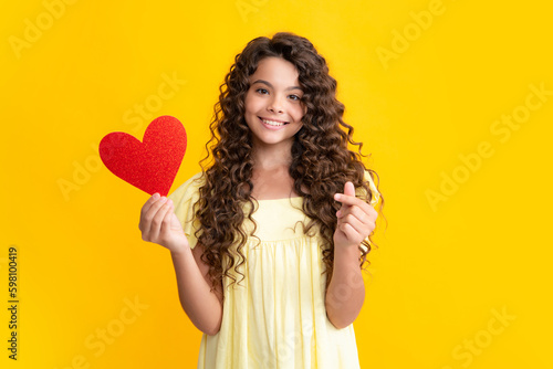 Lovely teenager portrait. Teenage girl hold shape heart, heart-shape sign. Child holding a red heart love holiday valentine symbol. Smiling girl.