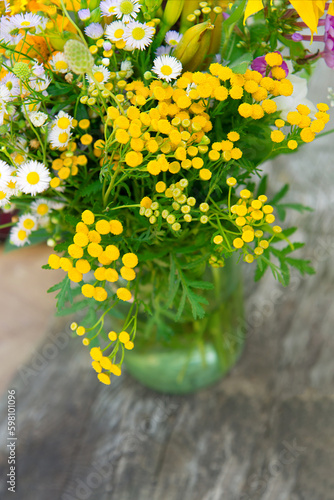 Bouquet of yellow flowers in a vase. Minimal floral frame made of yellow tansy flowers on a wooden background. Village theme in nature. Blank greeting card, invitation and envelope mockup. 