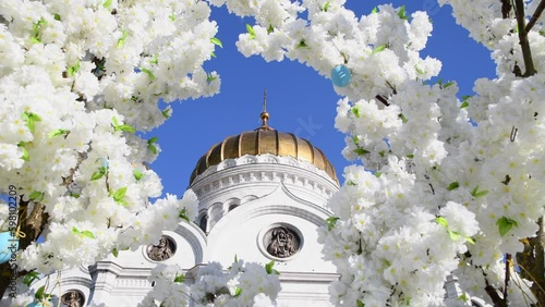 View of Cathedral of Christ the Saviour in Moscow, Russia through frame of white blooming flowers. Clear blue sky. Real time video. Easter holiday theme.